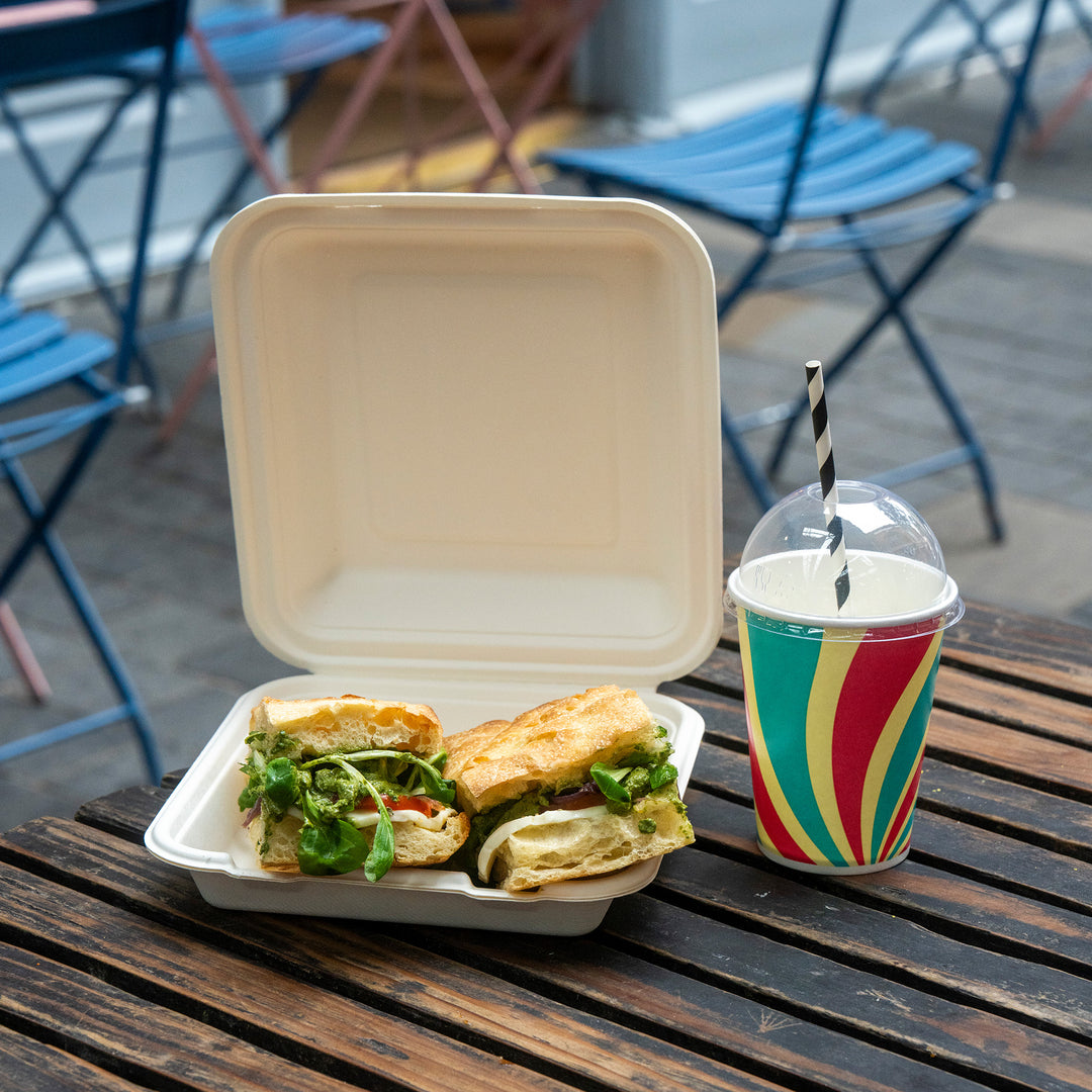 Packaging Wise 12oz patterned cold drink cup with RPET dome lid — perfect for grab-and-go cafés, paired with takeaway sandwich packaging on outdoor seating.