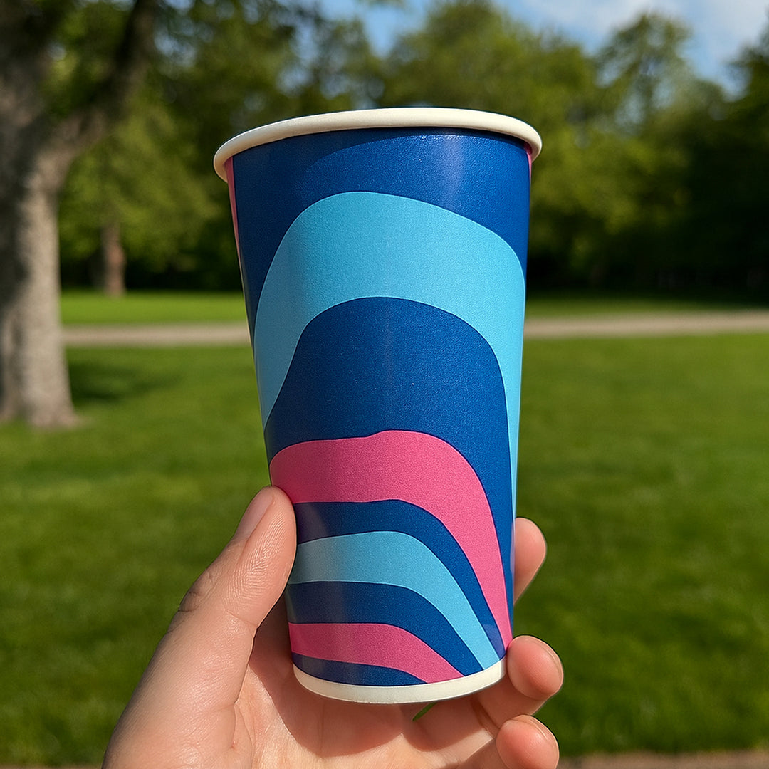 Packaging Wise 22oz patterned cold drink cup — bold multicolour design ideal for iced coffee, smoothies & soft drinks, shown outdoors in bright daylight.